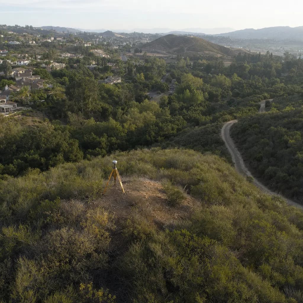 Brushy hillside parcel covered in chaparral and oaks with a GNSS tripod on the ridge